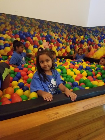 A camper takes a break from jumping around the ball pit for a photo